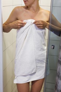 A beautiful girl in a white towel comes out from the shower. Relaxation after a hard day