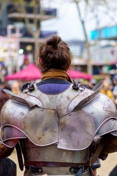 Back of a man dressed in medieval armor during a performance at a popular festival. Close-up view