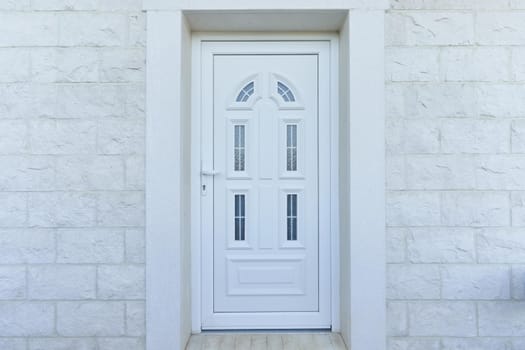 White front door and stone wall in a residential building.