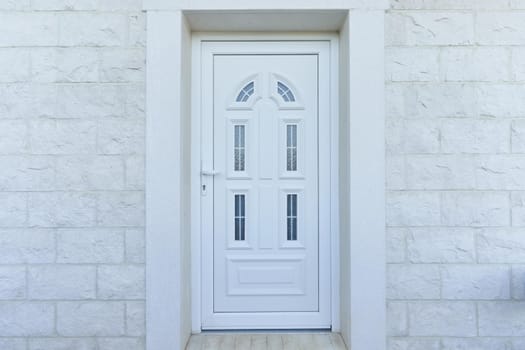 White front door and stone wall in a residential building.