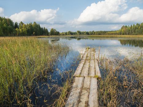 Wooden mooring for boats on Lake Kenozero. Beautiful landscape of clear water and autumn nature. Russia.