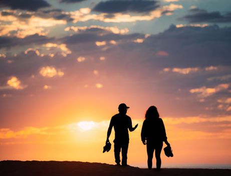 Couple at sunset beach in Santa Monica, California, United States of America. Sun and clouds in background.