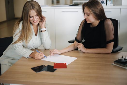 Woman choosing and buying car at car showroom. Car salesman helps them to make right decision. Female sign documents.