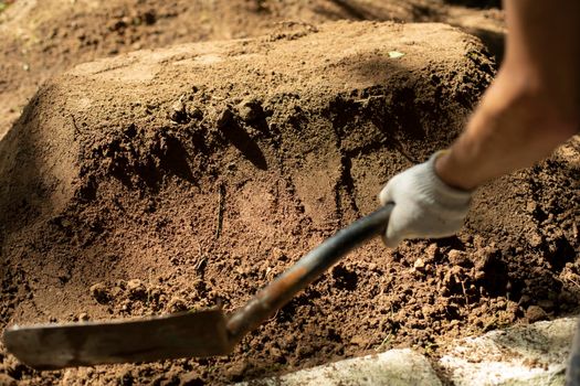 Undertaker strikes grave. Shovel and earth. Man is digging ground. Sand ramming. Garden tools.