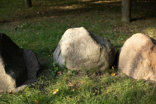 Stones in park. Cobblestones lie on grass. Landscape of city park.