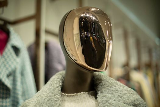 Golden mask on face of mannequin. Details of style and fashion. Mannequin in clothing store. Female figure.