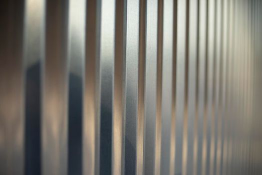 Texture fence. Steel fence of silver color. Horizontal lines. Reflection of light from metal.