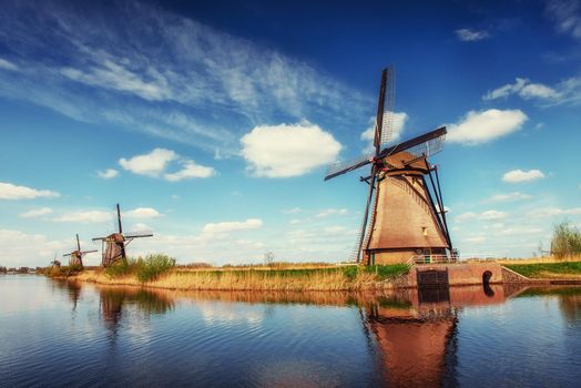 Colorful spring day with traditional Dutch windmills canal in Rotterdam. Wooden pier near the lake shore. Holland. Netherlands.