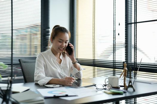 Portrait asian business woman making a phone call and smiling while working it office.