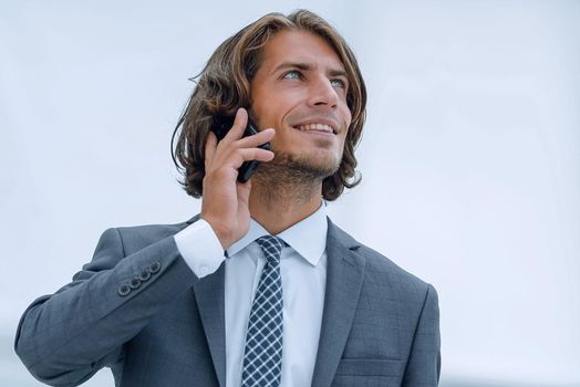 closeup.a successful businessman with travel suitcase talking on the phone.