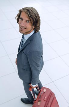 side view.smiling businesswoman with travel suitcase looking at the camera .photo with copy space