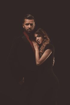 Portrait of young couple in love posing at studio dressed in classic clothes