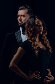 Portrait of a beautiful young couple in love posing at studio over dark background.