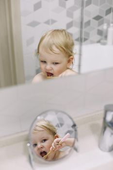 little funny girl brushing her teeth in the bathroom