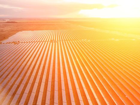 Aerial top view of a solar panels power plant. Photovoltaic solar panels at sunrise and sunset in countryside from above. Modern technology, climate care, earth saving, renewable energy concept