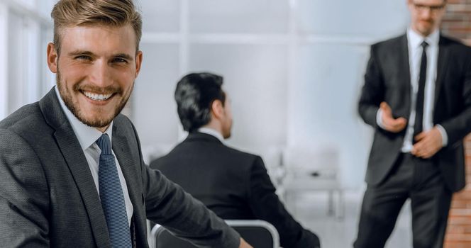 Cheerful male manager turning around and smiling at camera, when business coach explaining graph.