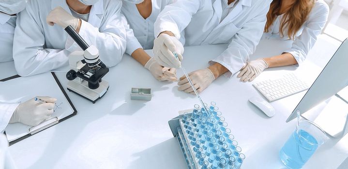 young medical doctors are working with test tubes and microscope at the lab