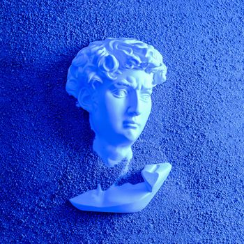 Bust head of David plaster antique in the sand on the beach. Minimal concept of futurism, cyberpunk and vaporway.