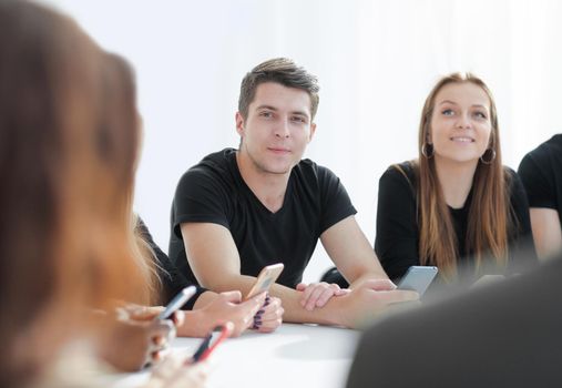 close up. casual young people look at the screens of their smartphones sitting at the table