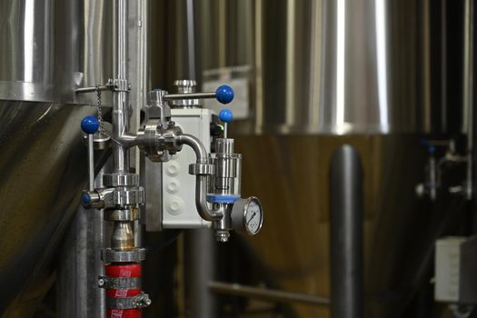 Taps in equipment with a manometer on a blurred background of a beer production