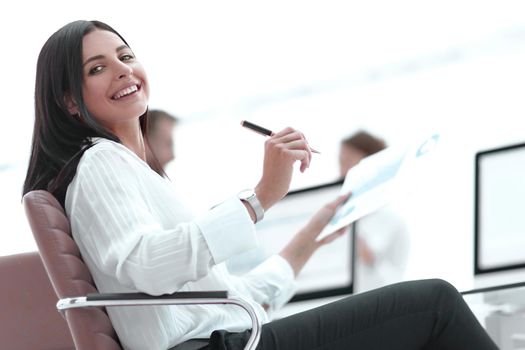 smiling business woman with financial documents sitting at work desk. business concept.