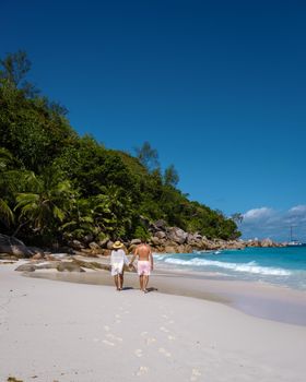 Anse Georgette Praslin Seychelles, young couple of men and woman on a tropical beach during a luxury vacation in Seychelles. Tropical beach Anse Georgette Praslin Seychelles.