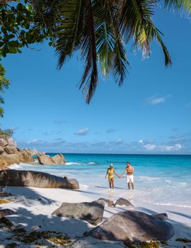 Anse Georgette Praslin Seychelles, young couple of men and woman on a tropical beach during a luxury vacation in Seychelles. Tropical beach Anse Georgette Praslin Seychelles.