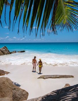 Anse Georgette Praslin Seychelles, young couple of men and woman on a tropical beach during a luxury vacation in Seychelles. Tropical beach Anse Georgette Praslin Seychelles.