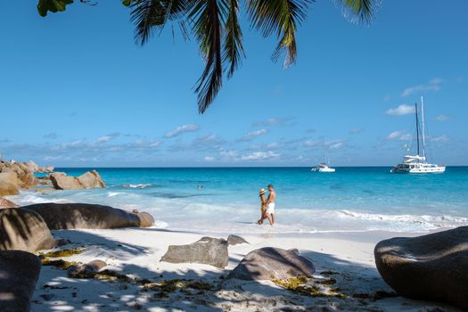 Anse Georgette Praslin Seychelles, young couple of men and woman on a tropical beach during a luxury vacation in Seychelles. Tropical beach Anse Georgette Praslin Seychelles.