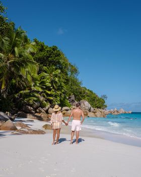 Anse Georgette Praslin Seychelles, young couple of men and woman on a tropical beach during a luxury vacation in Seychelles. Tropical beach Anse Georgette Praslin Seychelles.