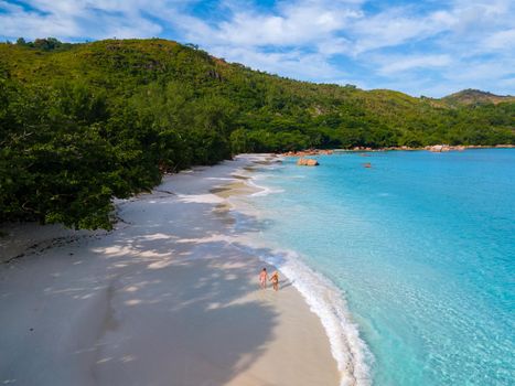 Anse Lazio Praslin Seychelles, a young couple of men and women on a tropical beach during a luxury vacation in Seychelles. Tropical beach Anse Lazio Praslin Seychelles