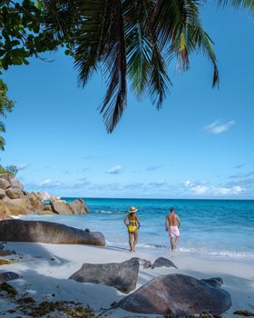 Anse Georgette Praslin Seychelles, young couple of men and woman on a tropical beach during a luxury vacation in Seychelles. Tropical beach Anse Georgette Praslin Seychelles.
