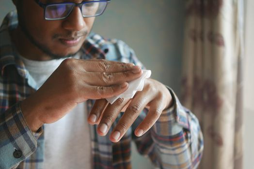 man disinfecting his hands with a wet wipe