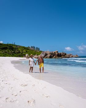 Anse Cocos La Digue Seychelles, a young couple of men and women on a tropical beach during a luxury vacation in Seychelles. Tropical beach Anse Cocos La Digue Seychelles.