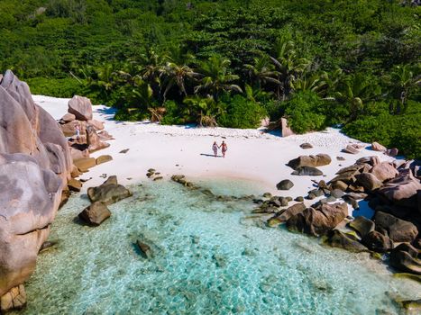 Anse Cocos La Digue Seychelles, a young couple of men and women on a tropical beach during a luxury vacation in Seychelles. Tropical beach Anse Cocos La Digue Seychelles.