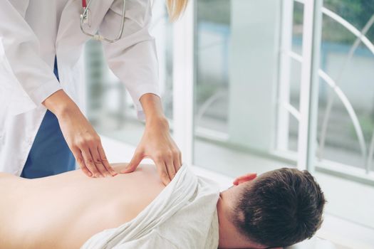 Woman doctor is examining male patient in hospital office. Healthcare and medical service.