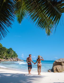 Anse Patates, La Digue Seychelles, a young couple of men and women on a tropical beach during a luxury vacation in Seychelles. Tropical beach Anse Patates, La Digue Seychelles