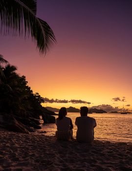 Anse Patates, La Digue Seychelles, a young couple of men and women on a tropical beach during a luxury vacation in Seychelles. Tropical beach Anse Patates, La Digue Seychelles