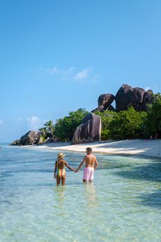 Anse Source d'Argent, La Digue Seychelles, a young couple of men and women on a tropical beach during a luxury vacation in Seychelles. Tropical beach Anse Source d'Argent, La Digue Seychelles