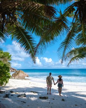 Anse Patates, La Digue Seychelles, a young couple of men and women on a tropical beach during a luxury vacation in Seychelles. Tropical beach Anse Patates, La Digue Seychelles