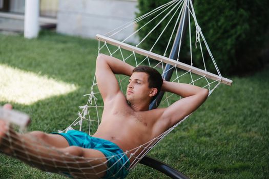 Handsome man resting in the hammock at the back yeard.