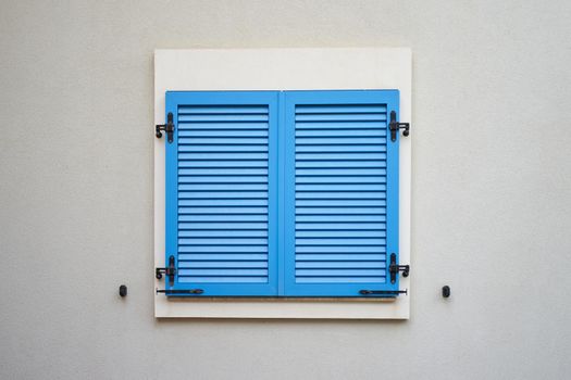 Blue plastic window shutters on a wall of residential building.