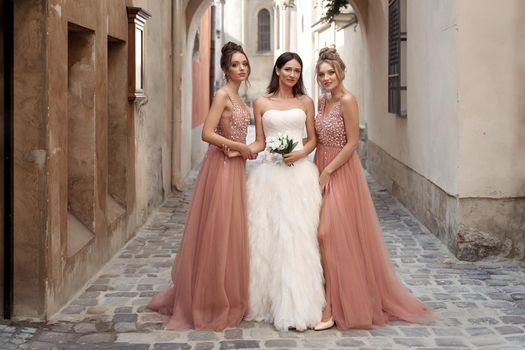Beautiful bride and bridesmaids in gorgeous elegant stylish silver dress decorated with sequins sparkles. Wedding day in old beautiful European city.