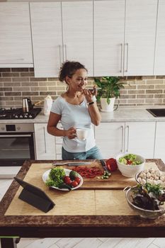 Young woman in the kitchen pauses in the preparation of salad while talking on the phone