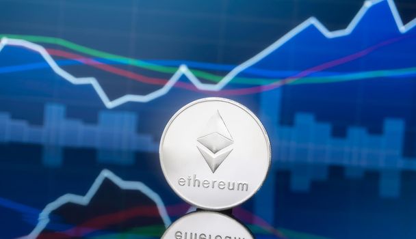 Ethereum (ETH) and cryptocurrency investing concept - Physical metal ethereum coins with global trading exchange market price chart in the background.