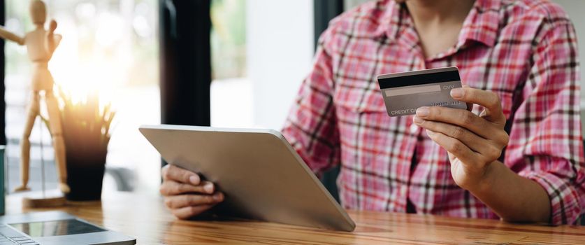 Close up of black girl hold bank credit card and type on digital tablet, shopping online using computer, buying goods or ordering online, entering bank accounts and details in online banking offer.