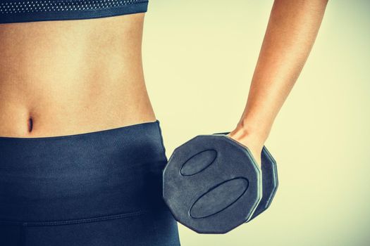 Sporty woman workout with dumbbell on clear background. Healthy lifestyle and exercising.