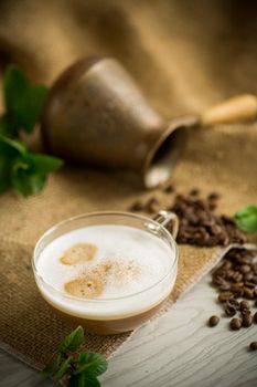 Cup of coffee latte with heart shape and coffee beans on old wooden background