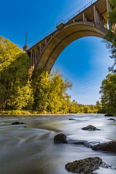 High long railway bridge over small river full of big stones at sunny day