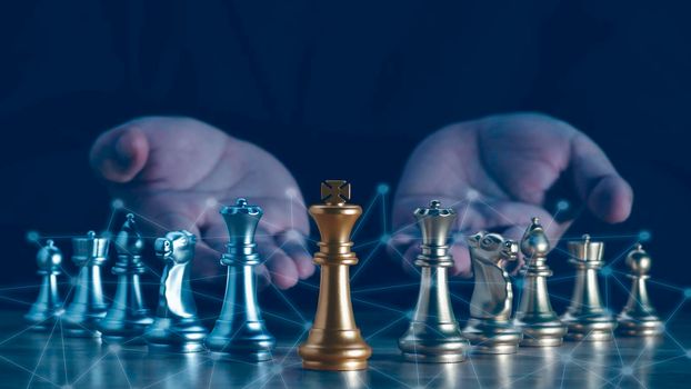 Hand of businessman holding the golden king chess to fighting silver king chess to play successfully in the competition with technolog network background. Management or leadership strategy concept.